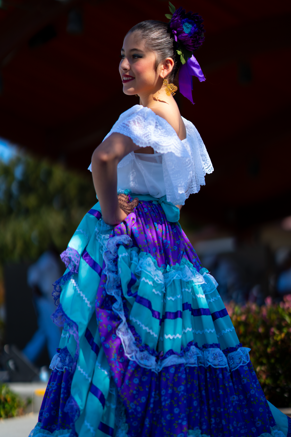 Dancer in a blue and white ruffled dress performs traditional Mexican folk dance.