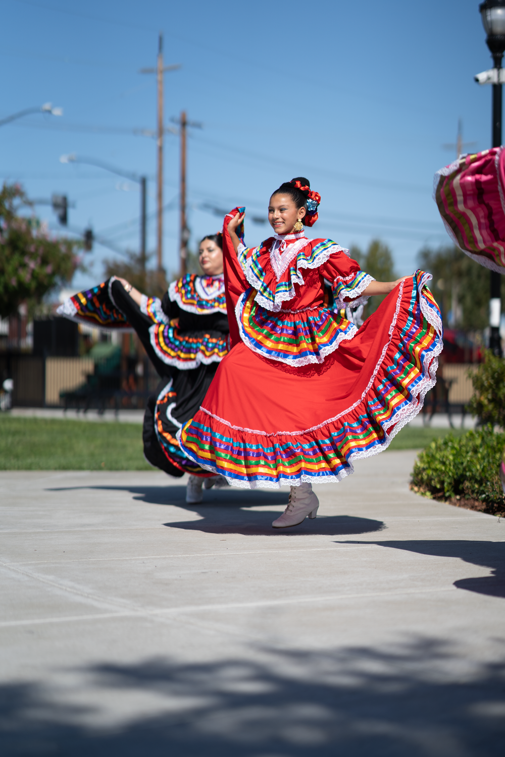 Dancers in vibrant red traditional Mexican dresses perform synchronized twirling movements.