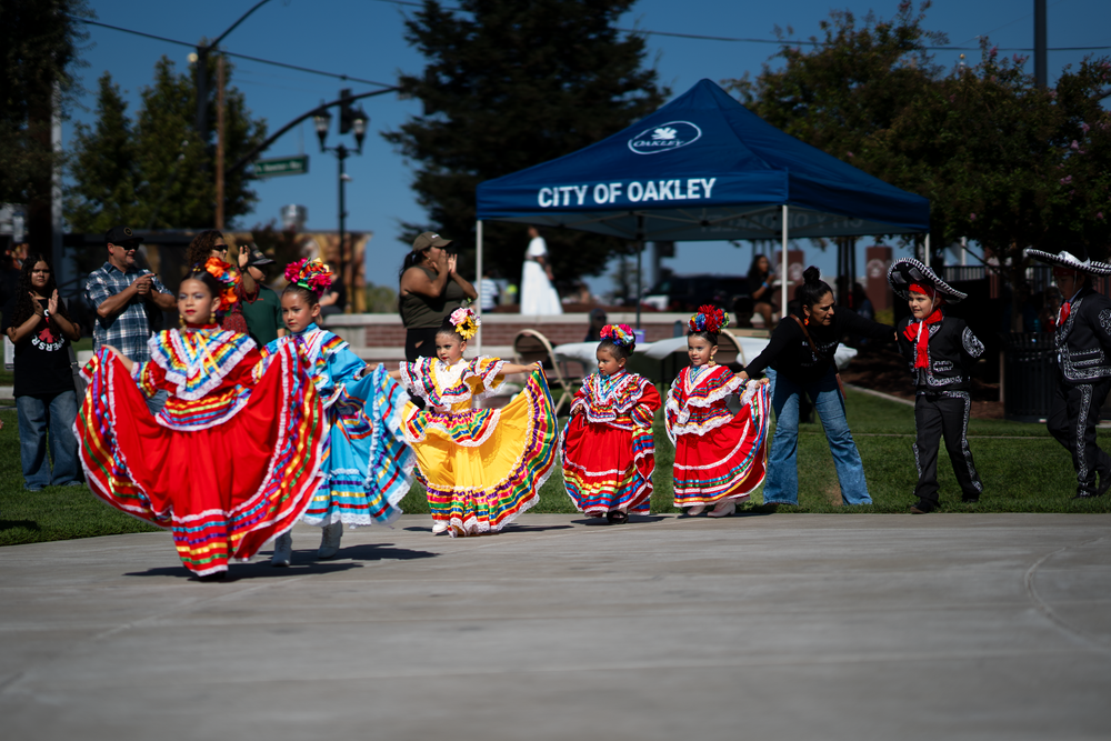 Colorful Mexican folk dancers perform in bright traditional dresses at a City of Oakley event.