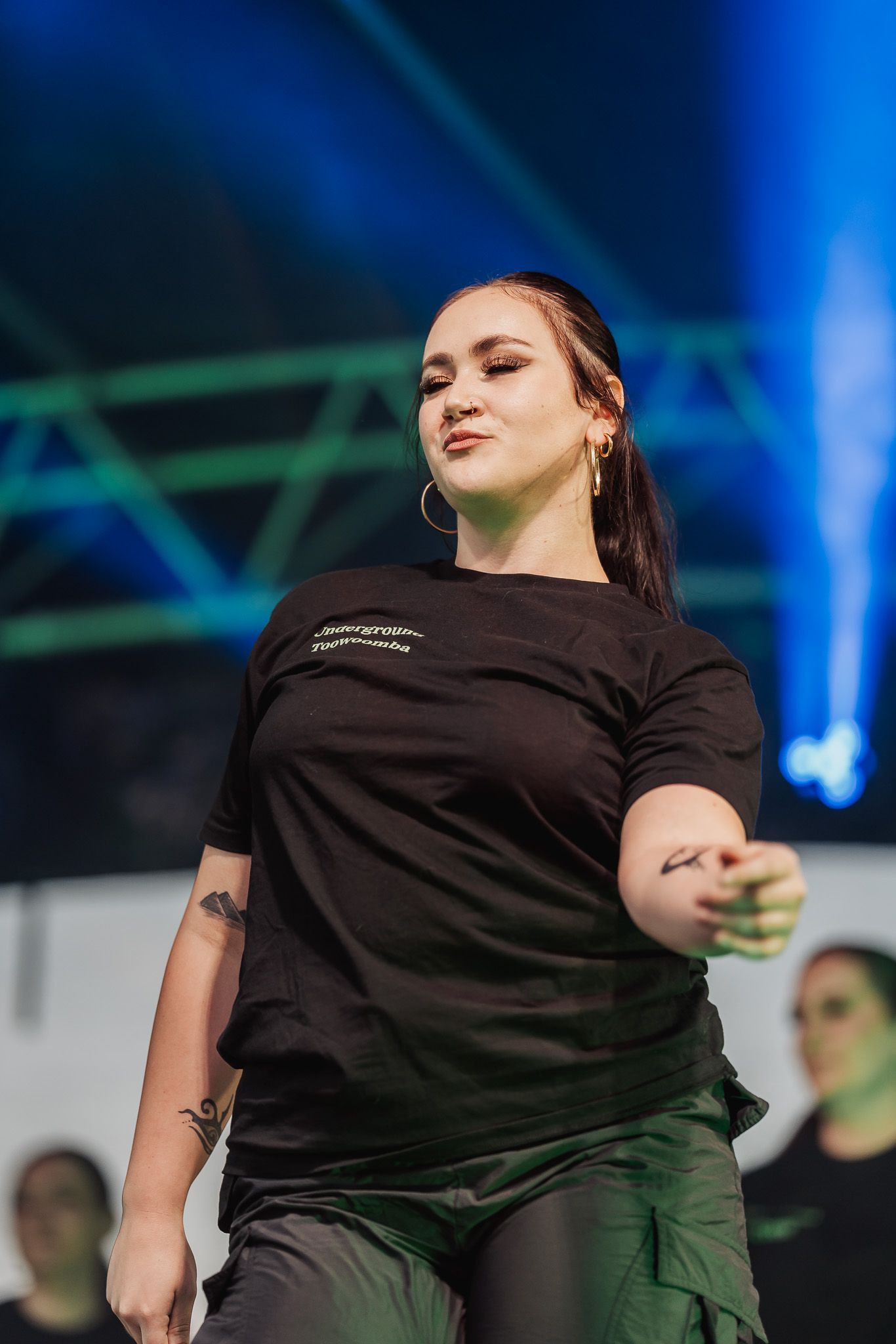 A series of performance shots showing someone in a black t-shirt dancing against a blue-lit stage background.