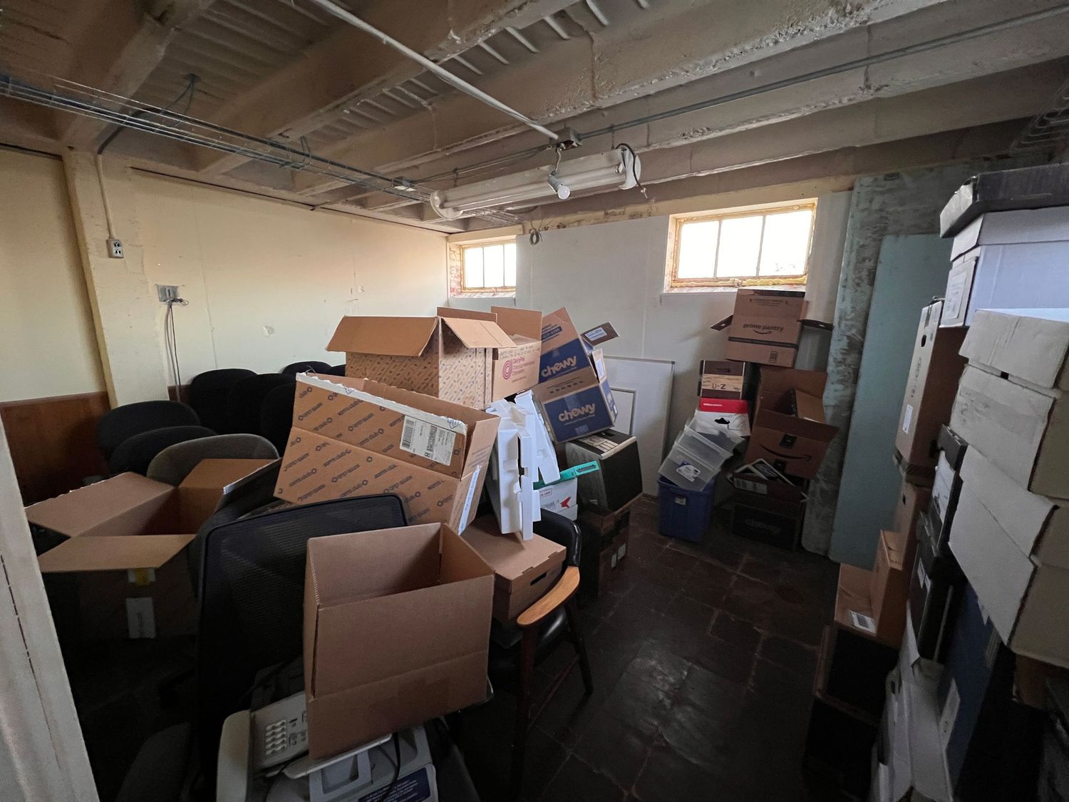 Dimly lit storage space with cardboard boxes and industrial shelving units.