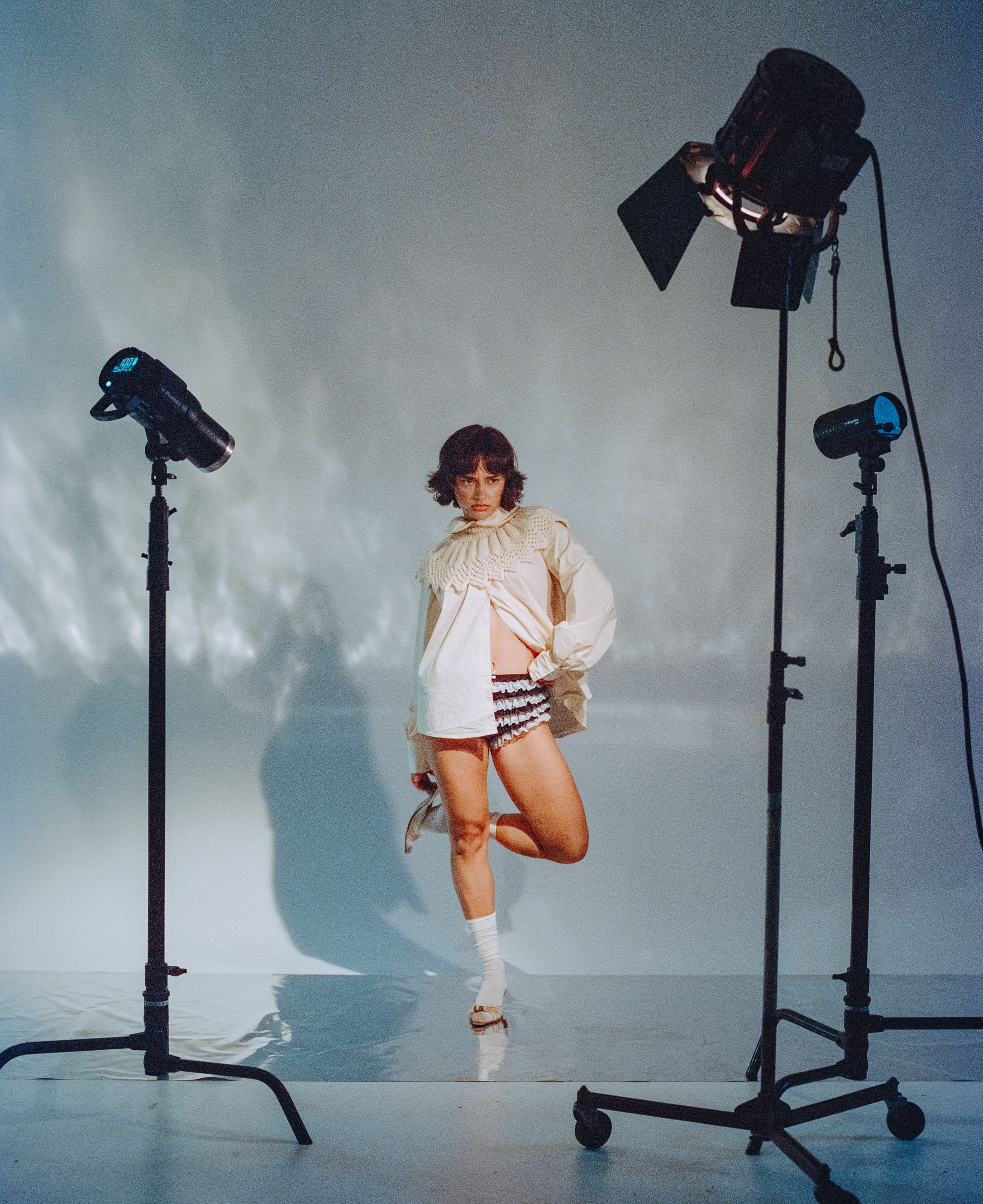 Dynamic fashion photo with studio lights showing model jumping in cream sweater.