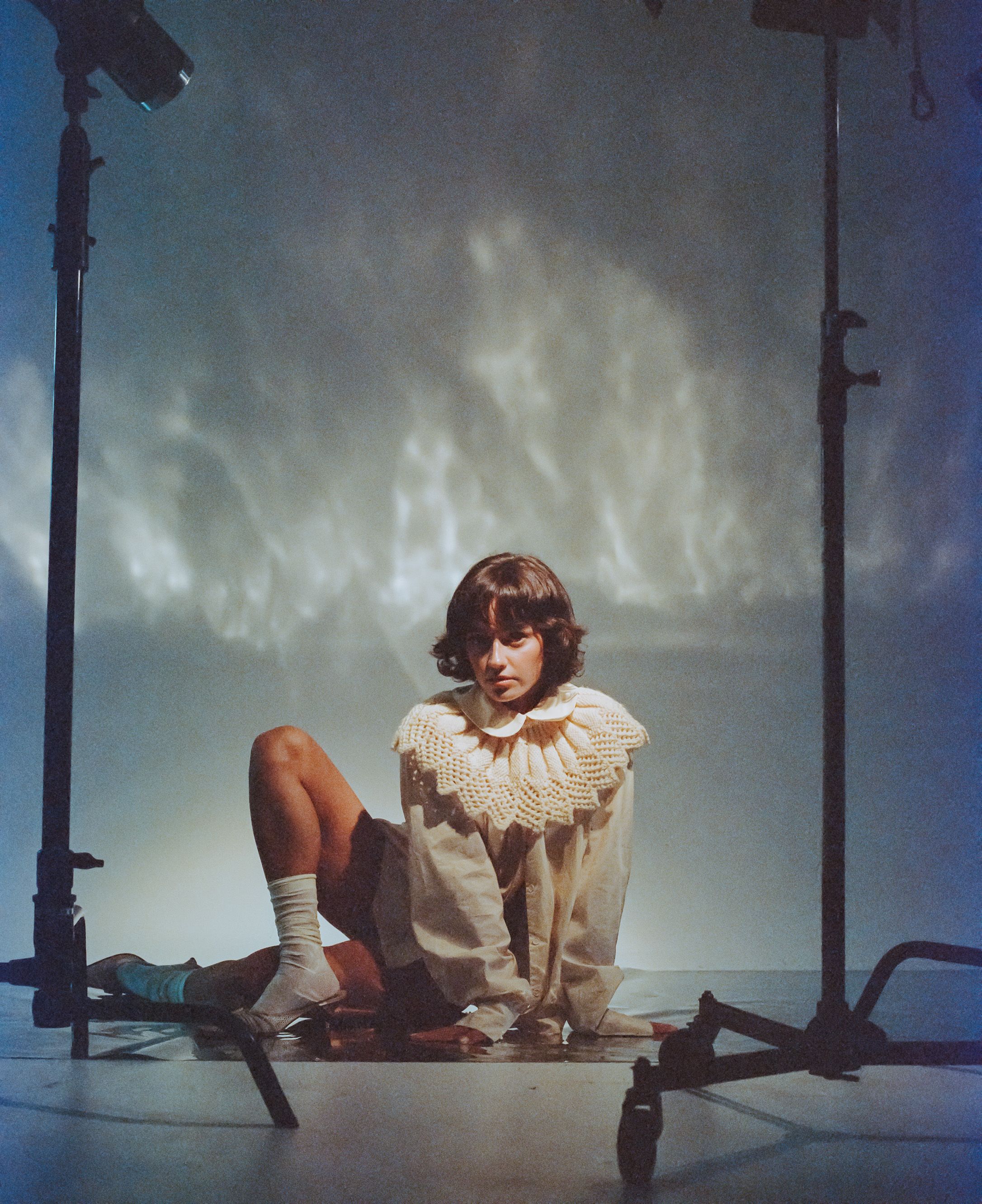 Artistic portrait with theatrical lighting showing person in vintage-style ruffled collar costume.