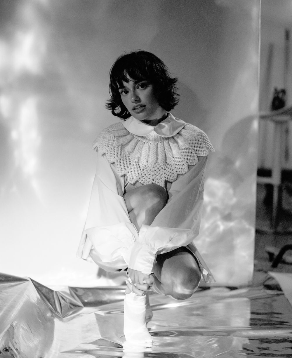 Artistic black and white studio photo featuring elaborate ruffled collar and posed composition.