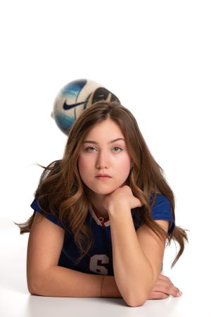 Young female with a soccer ball posing on a white backdrop.