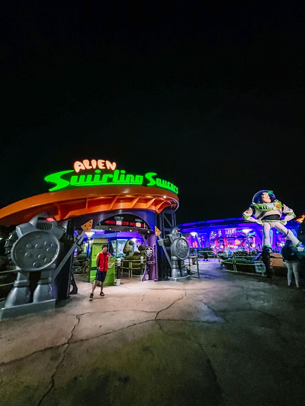 Alien Swirling Saucers illuminated ride entrance at Disney World's Toy Story Land at night with neon purple and green lights.