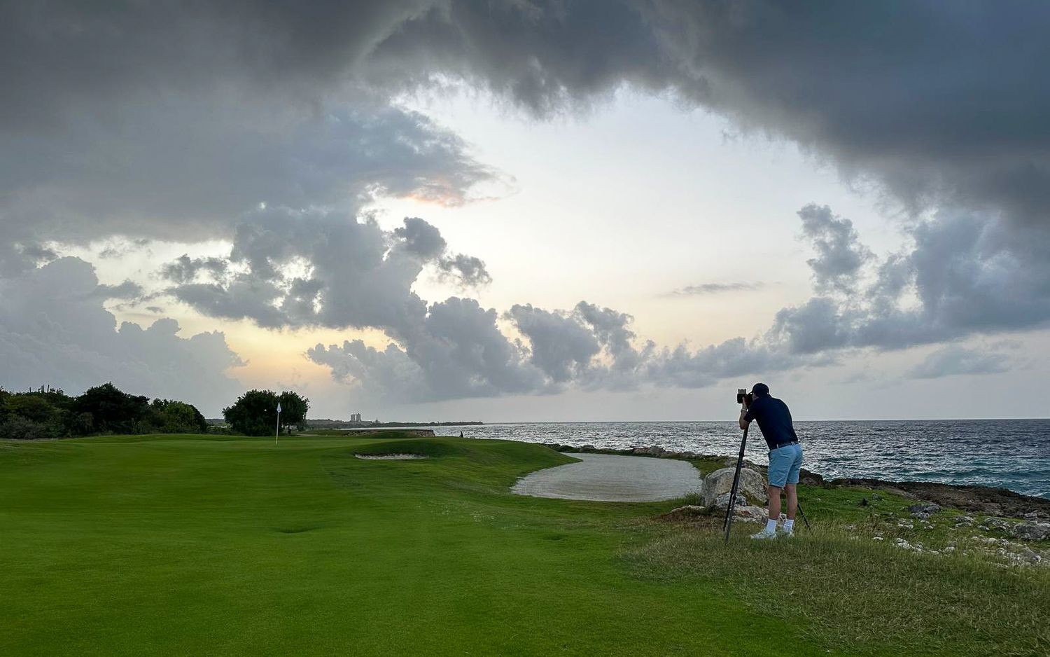 Peter van Weel taking a shot on coastal golf course with dramatic stormy sky and ocean in the background.