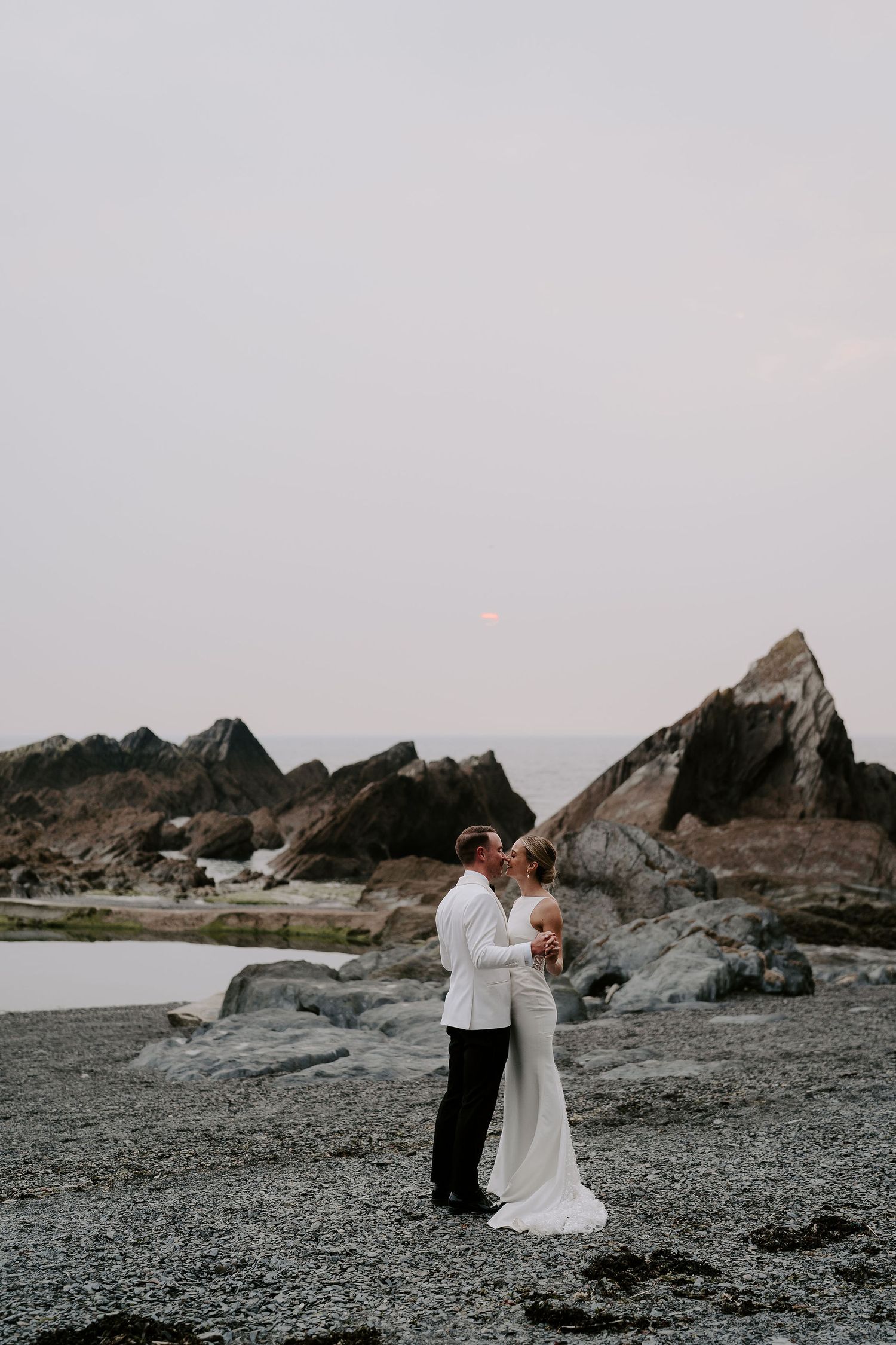 Bride and Groom kissing on beach during sunset at tunnels beach wedding venue in north Devon