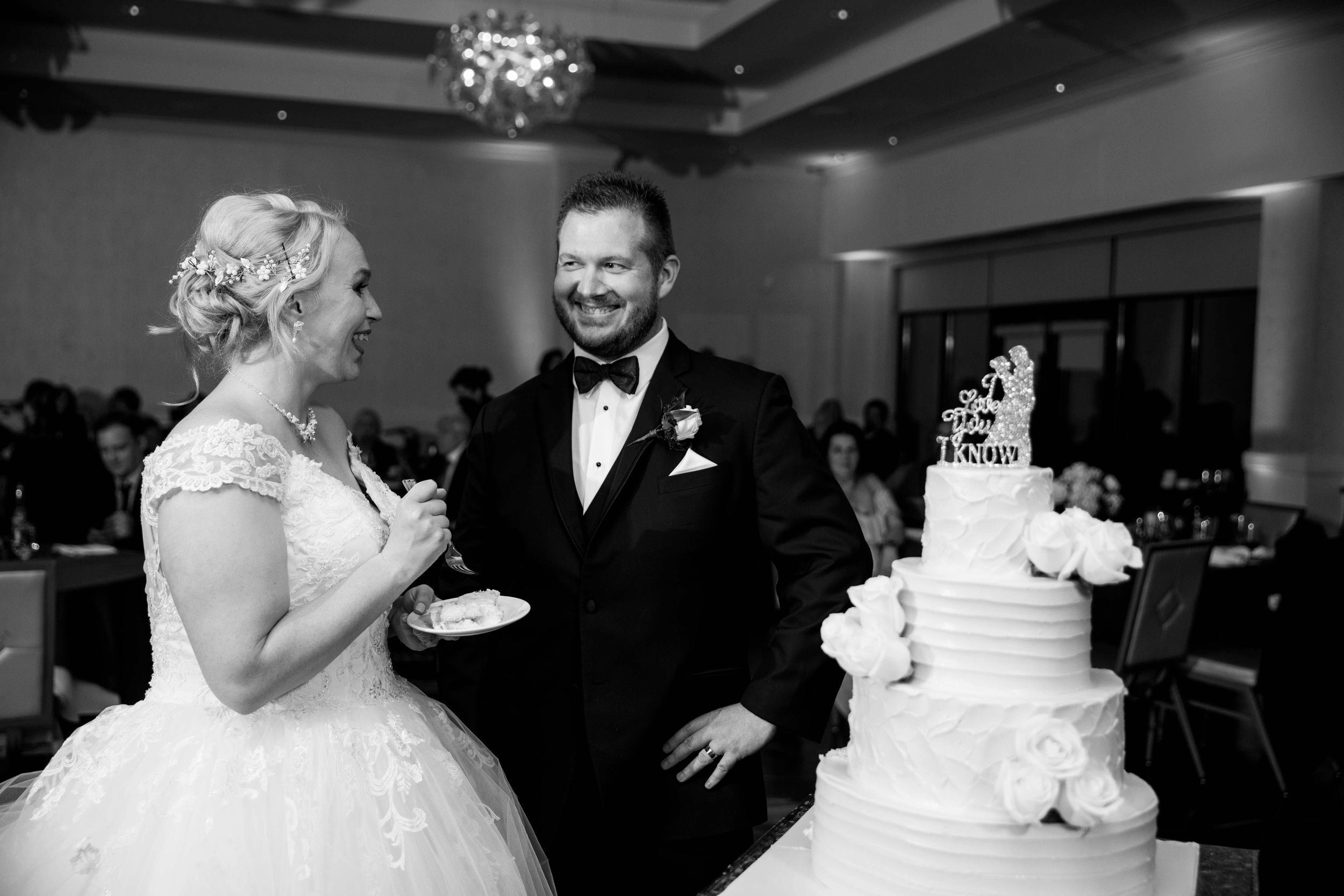 Newlyweds share a joyful moment beside their wedding cake during the reception.