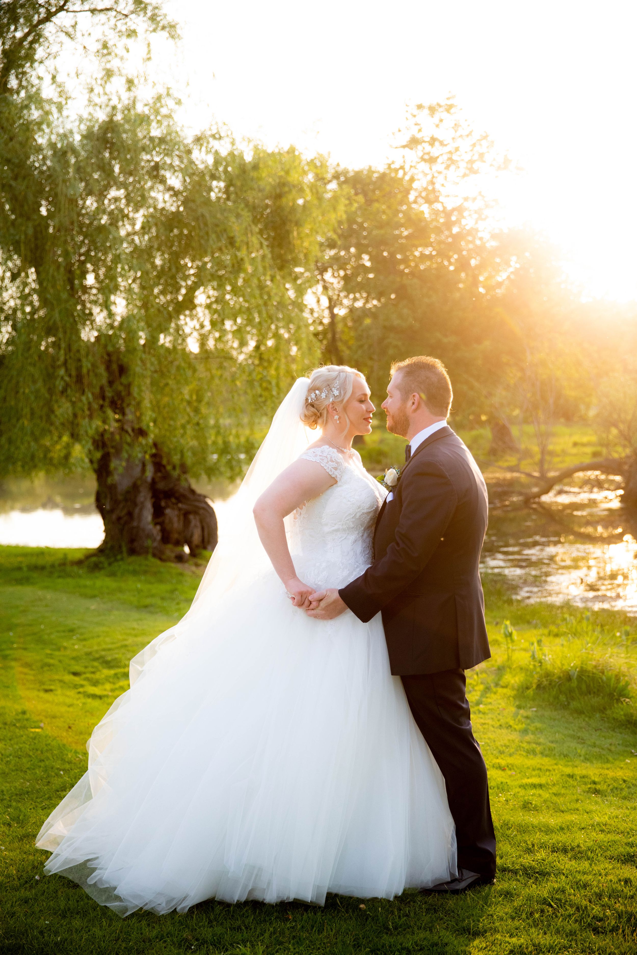 Sunset wedding portrait in garden setting with flowing white dress.