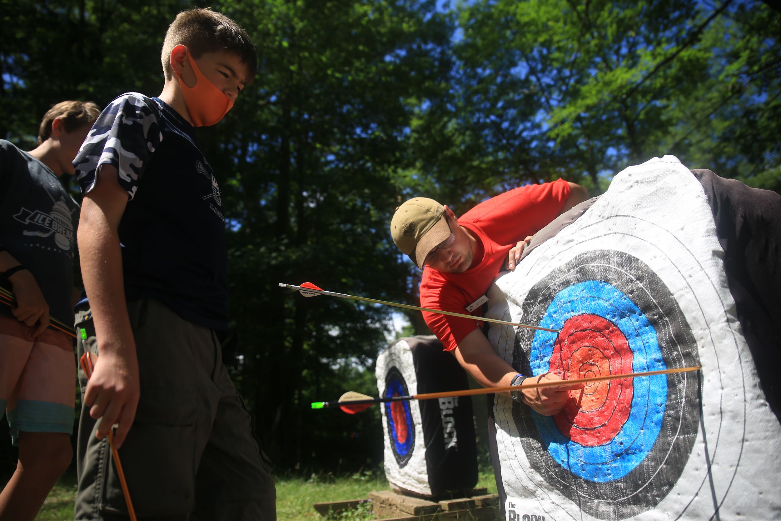 Archers examining arrows in target at outdoor archery range.