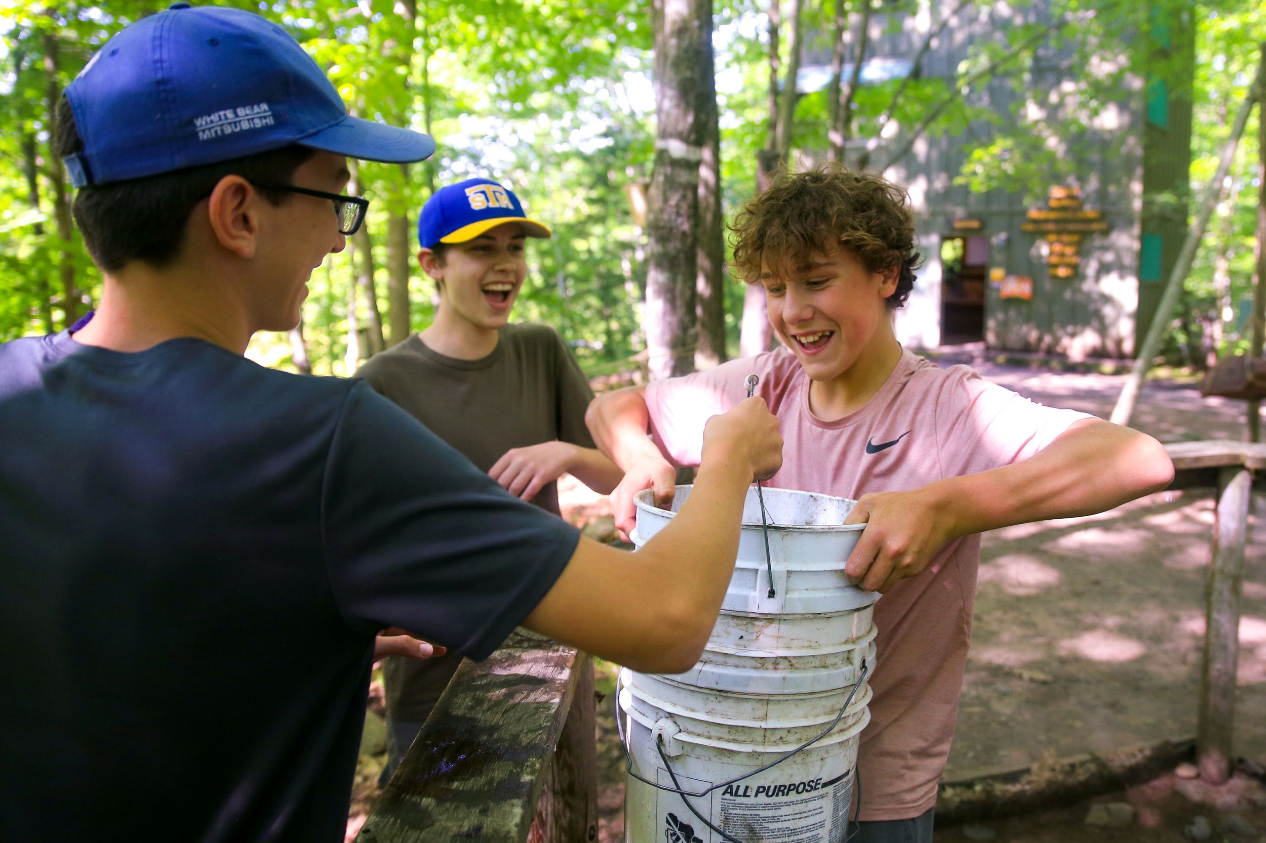 Summer camp participants engaged in an arm wrestling match outdoors.