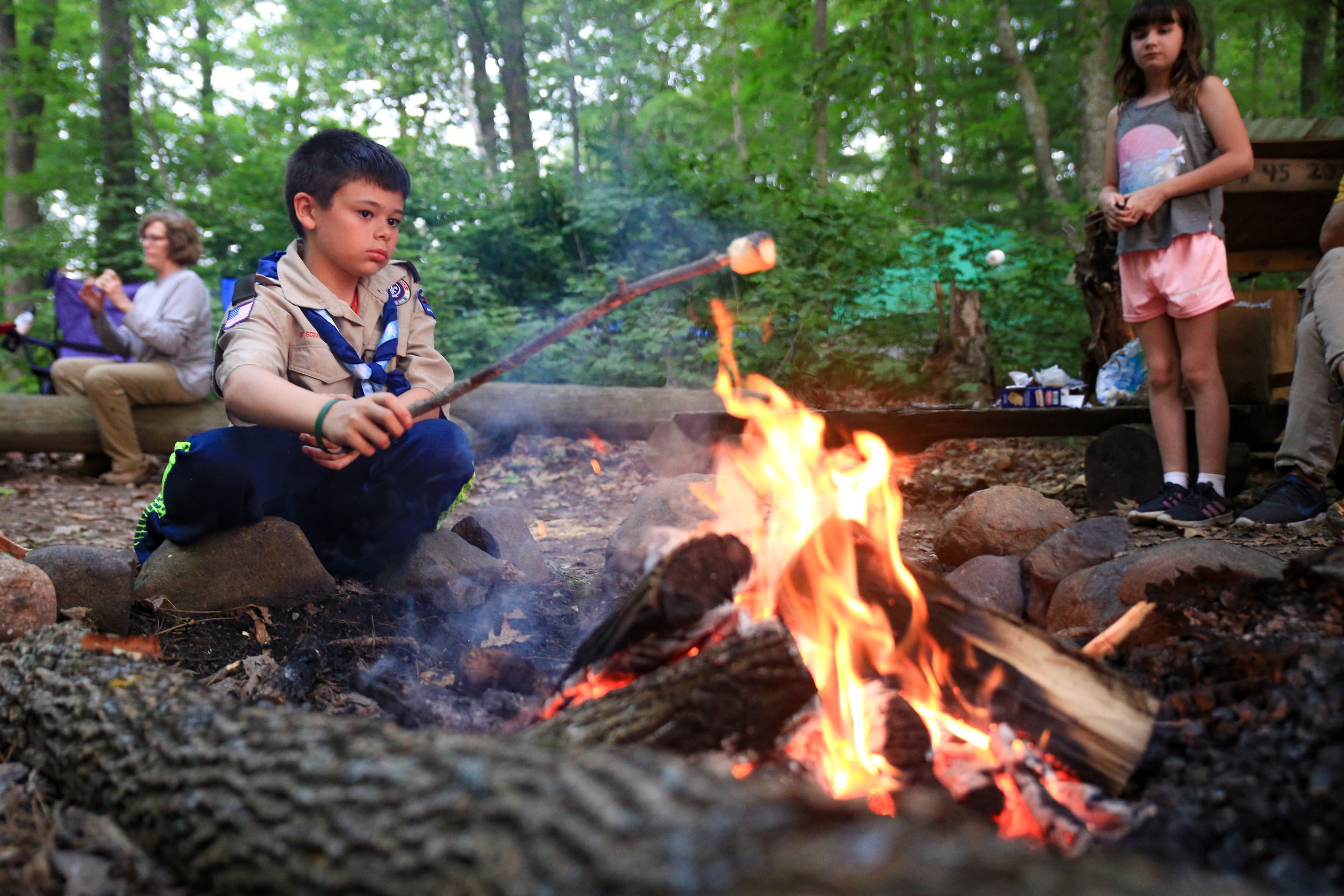 Campfire burning brightly in a stone fire pit surrounded by forest.