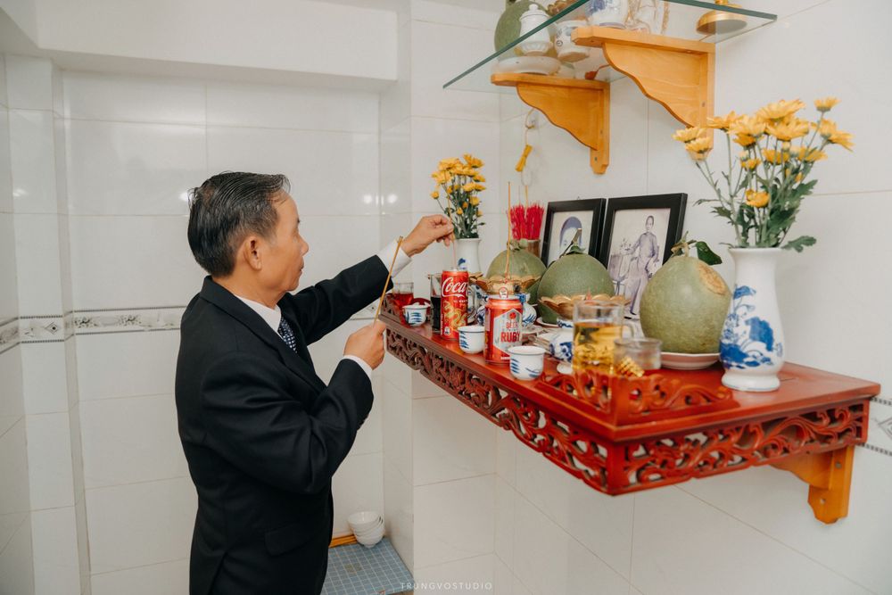 Elderly man makes offerings at a traditional Vietnamese ancestral altar during wedding ceremony.