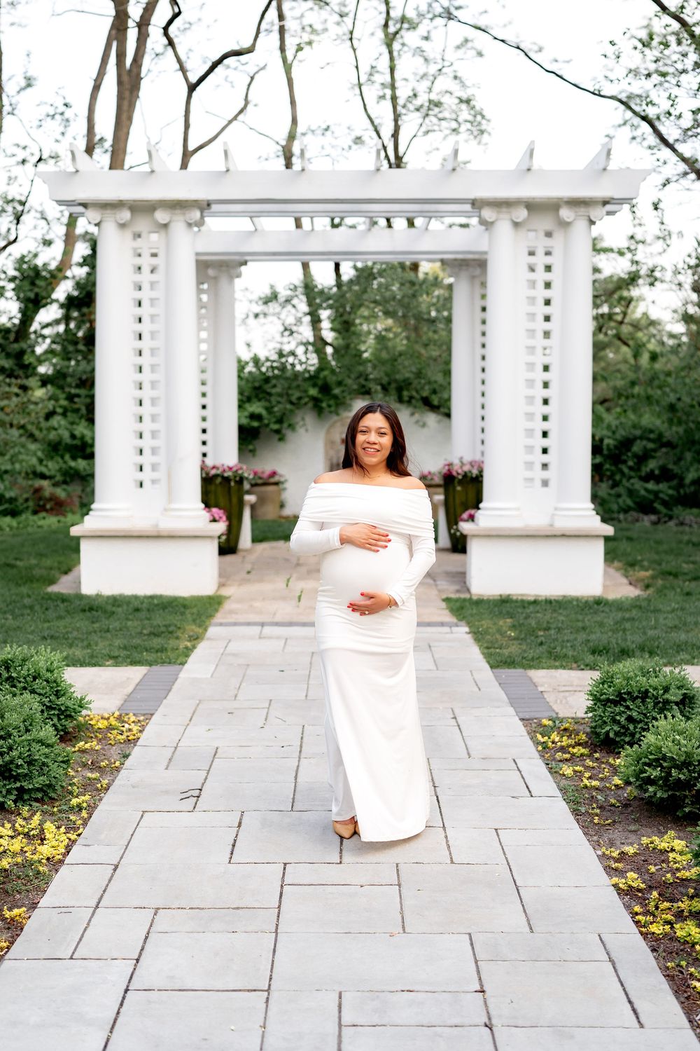 Elegant white stone patio with classic columns and landscaping creates a romantic wedding venue atmosphere.