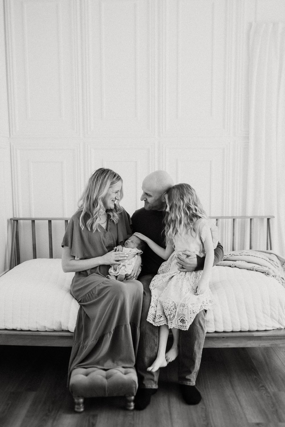 Black and white photo of a family sharing an intimate moment while sitting together on a daybed.