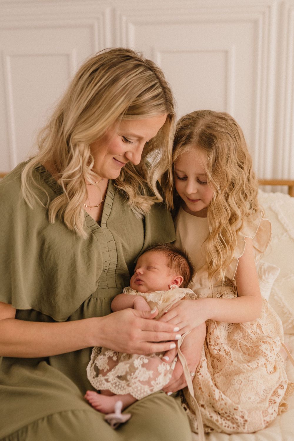 Tender family portrait showing gentle interaction on white paneled background.