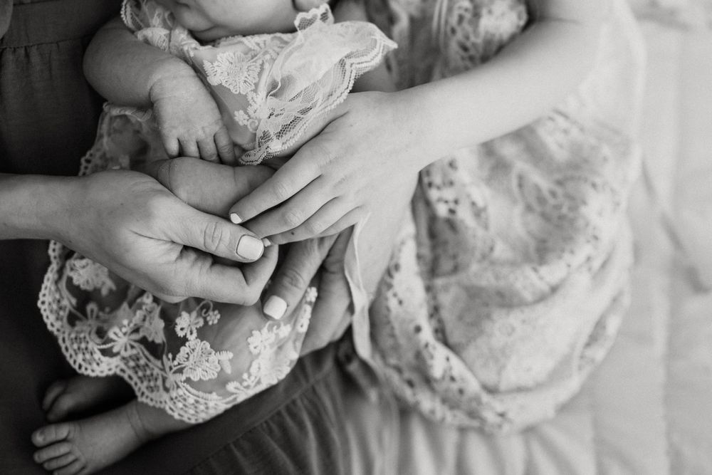 Black and white close-up photograph showing hands gently touching against delicate lace fabric.