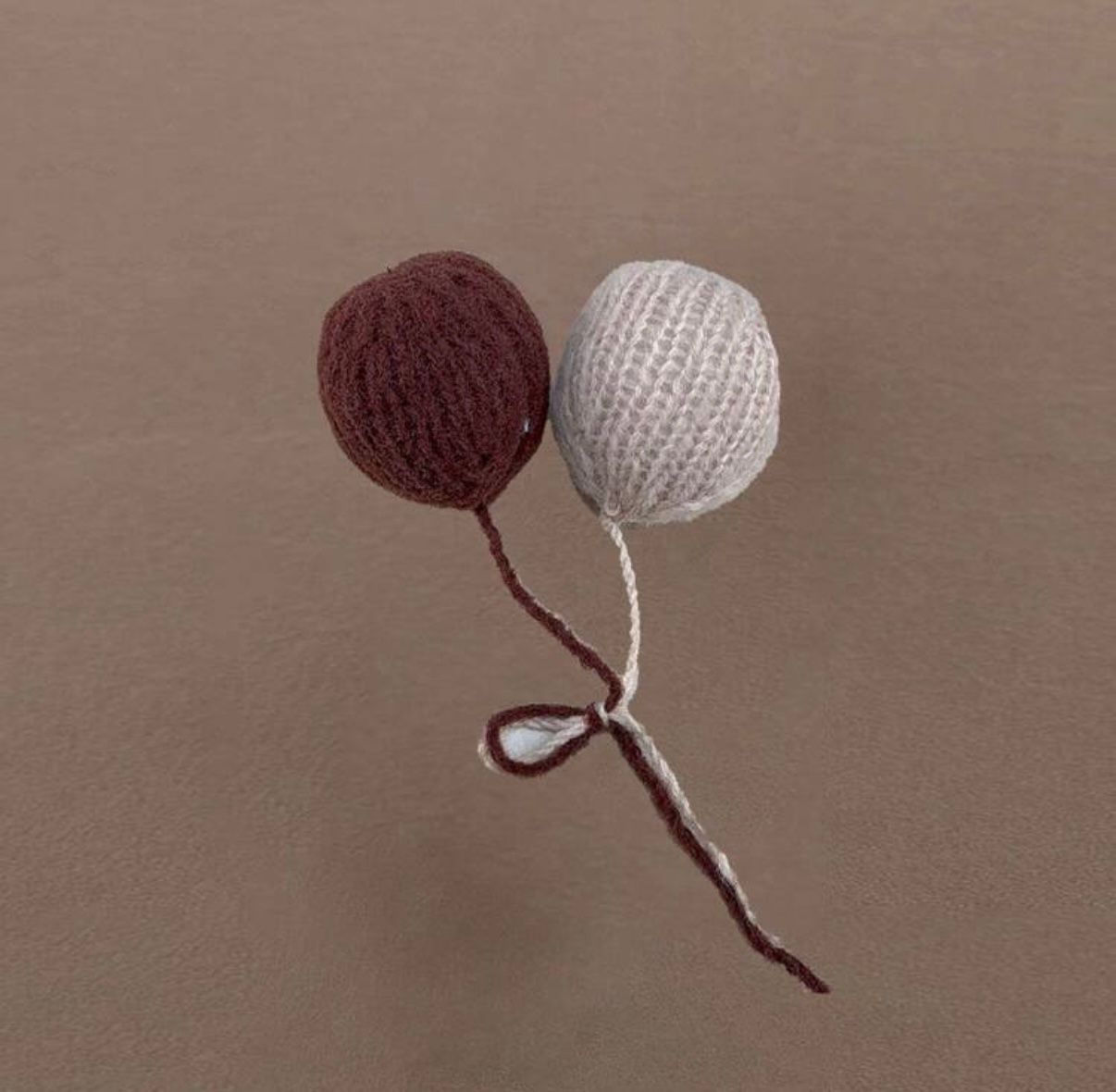 Knitted yarn pom poms in burgundy and cream colors arranged in a sequence.