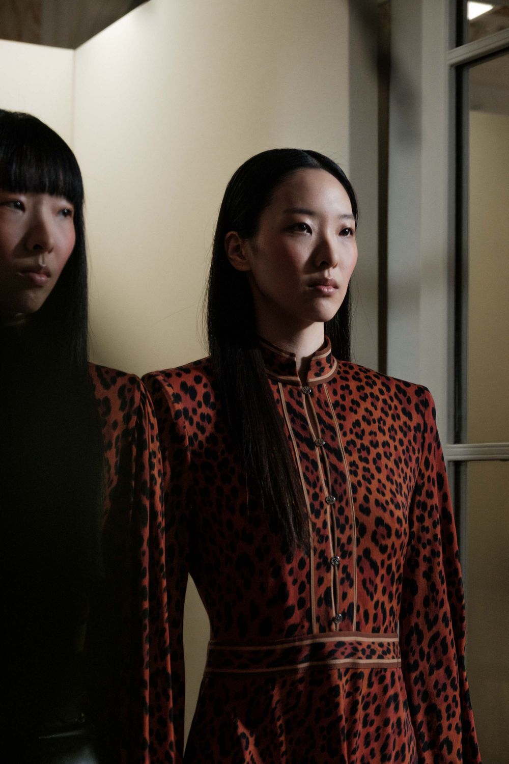 Model wearing a red and black leopard print high-neck dress in a fashion setting.