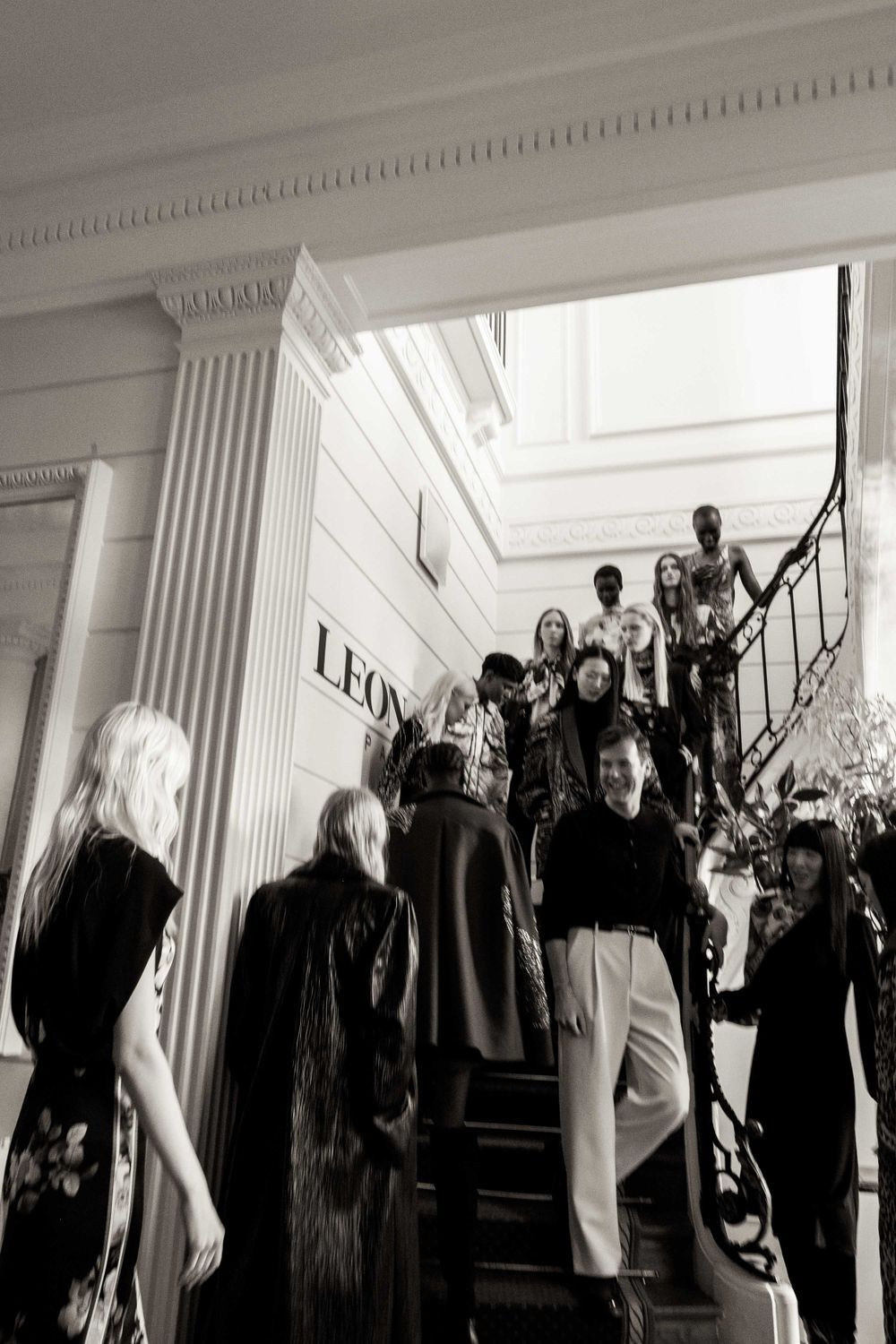 Group of models gathered on an elegant staircase at a fashion event.