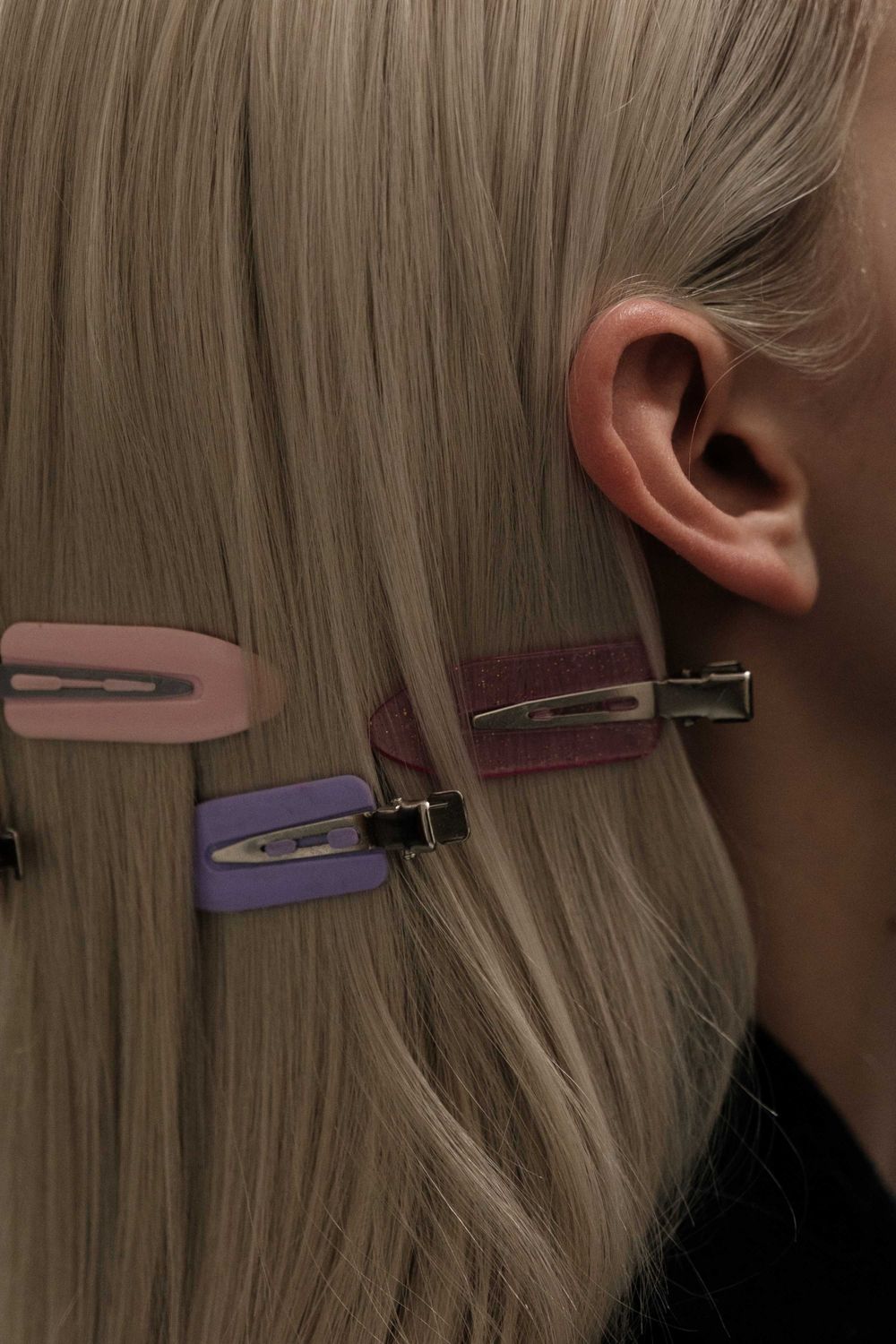 Colorful hair clips arranged on blonde hair in an artistic fashion photo.
