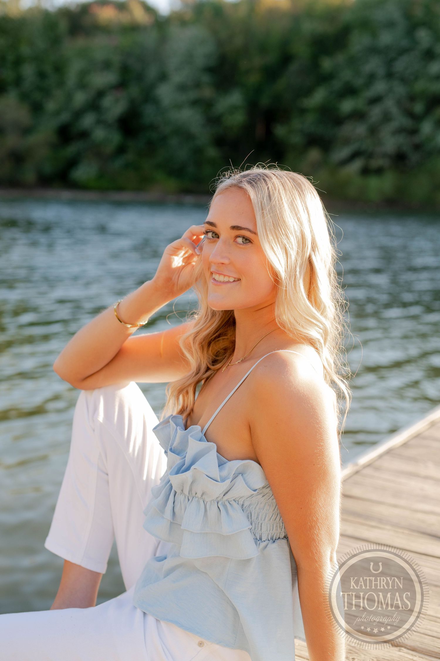 Candid lakeside portrait featuring natural smile and light blue summer outfit.