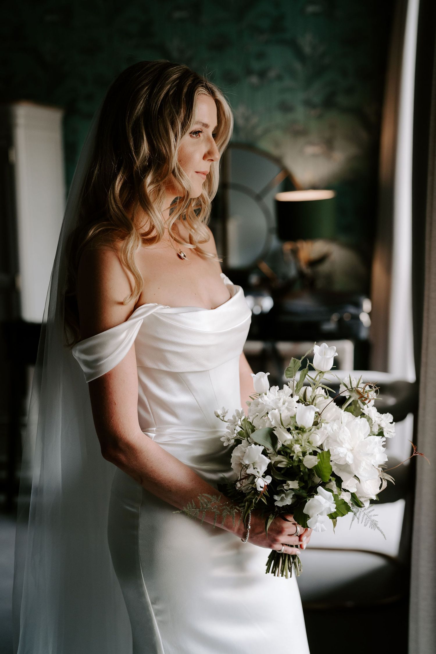 bride holding bouquet looking out the window at the Queensbury hotel in bath