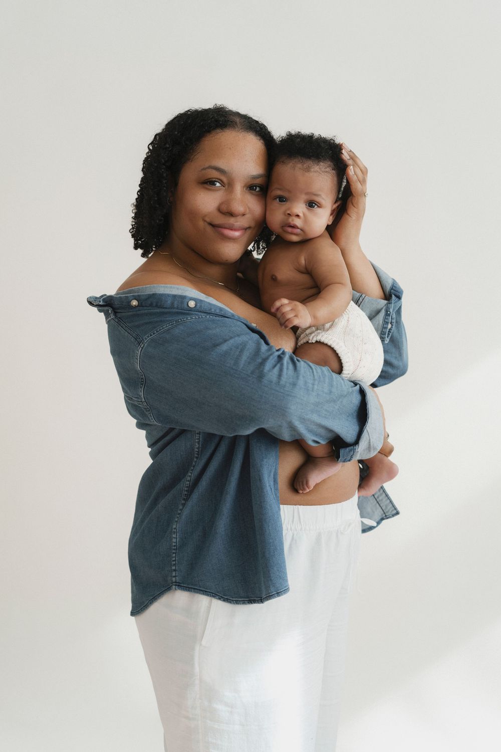 Studio portrait against white background showing joyful moment in casual denim and white outfit.