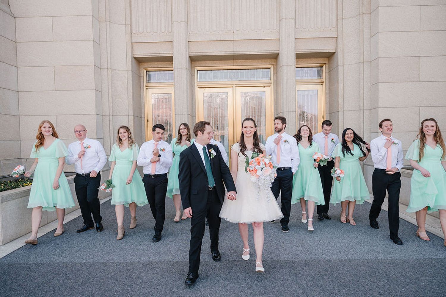 Wedding party poses together on stone steps with bridesmaids in mint green dresses and groomsmen in white shirts.