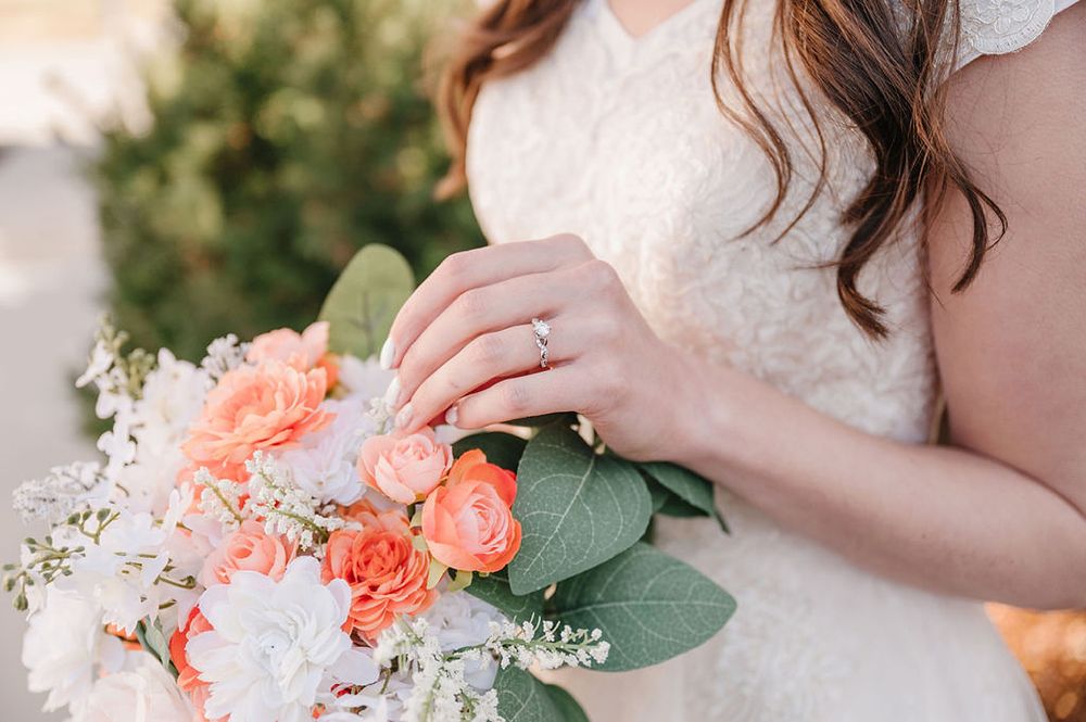 Close up of bridal bouquet featuring coral roses, white flowers and eucalyptus leaves.