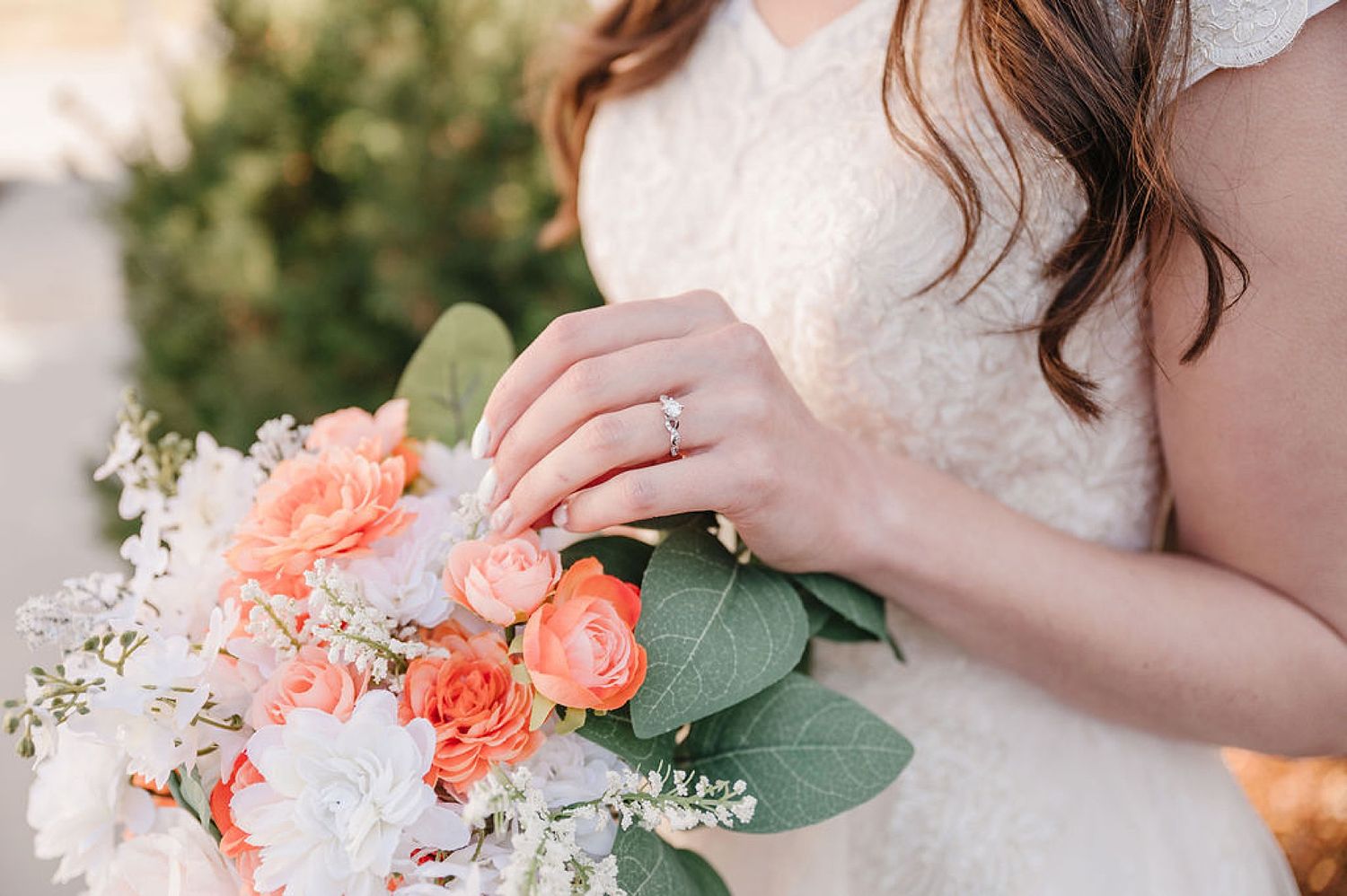Close up of bridal bouquet featuring coral roses, white flowers and eucalyptus leaves.