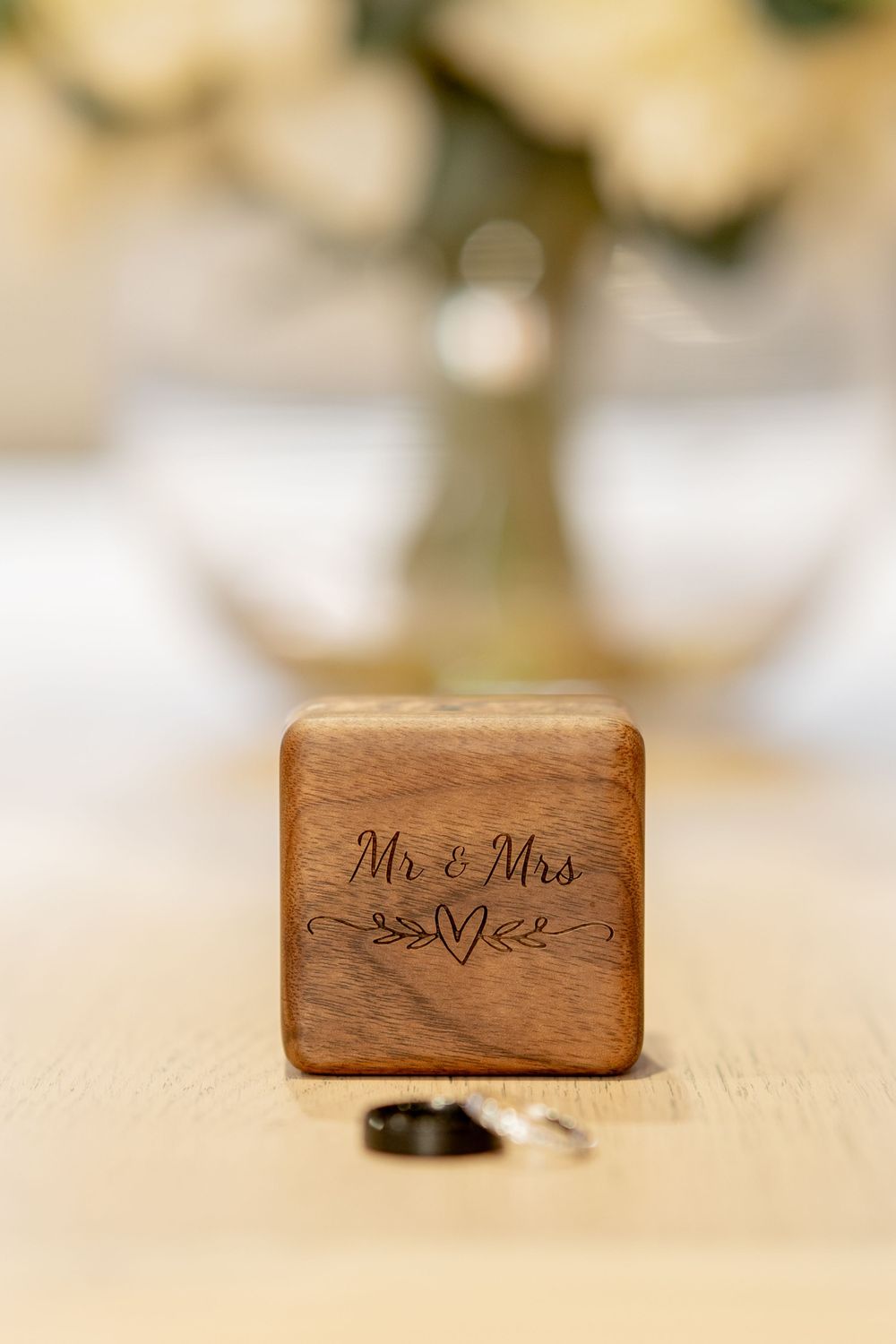Wooden ring box engraved with 'Mr & Mrs' and heart detail on light surface.