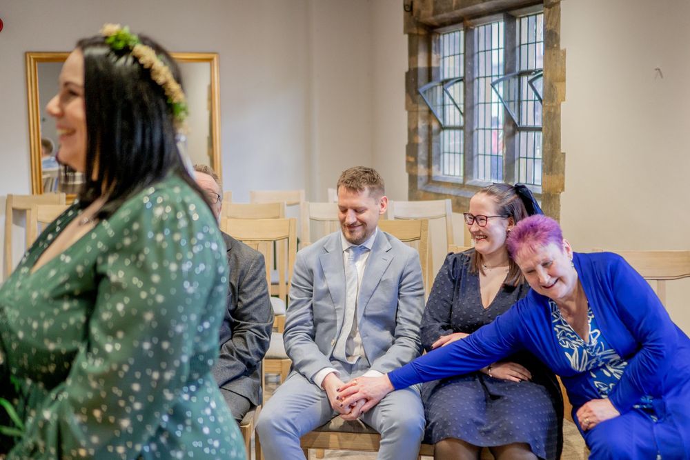 Wedding guests share a candid laughing moment in a bright indoor venue.