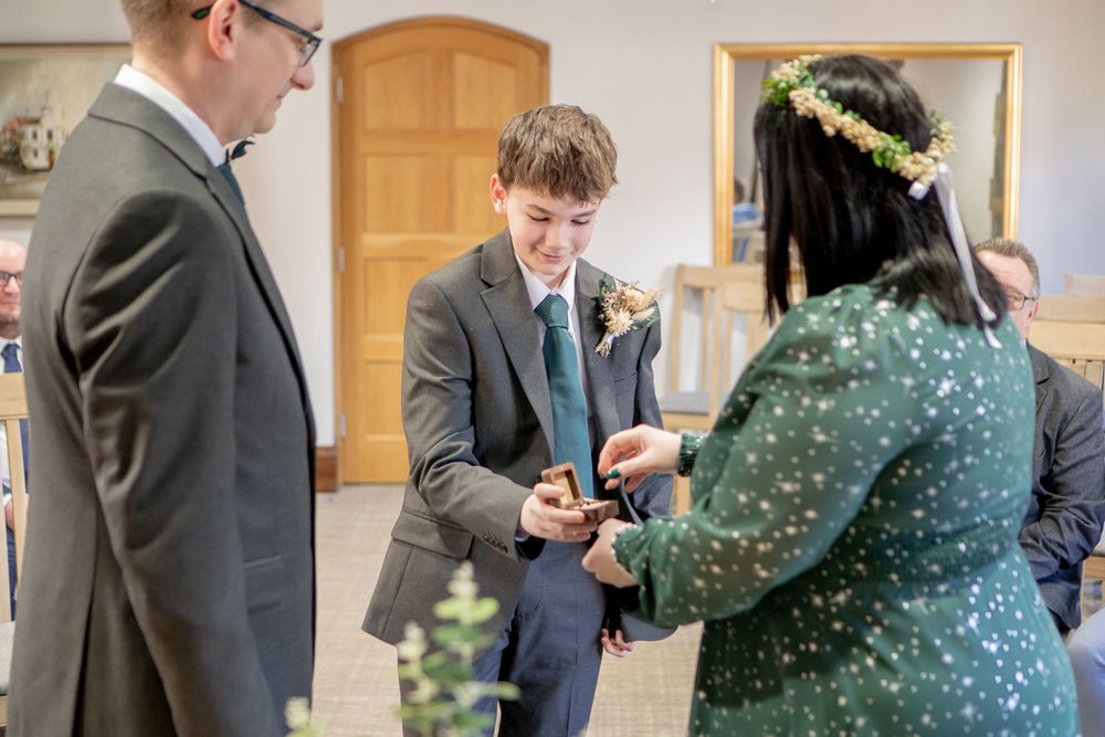 An intimate wedding ceremony moment as a couple exchanges rings with witnesses present.