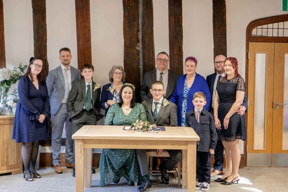 A group photo at a wooden table with exposed timber beams and decorative elements in a rustic setting.