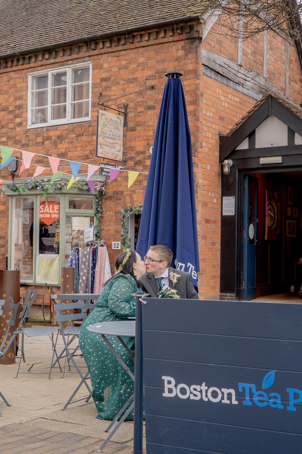 Outdoor cafe scene at Boston Tea Party with brick building and colorful bunting in background.