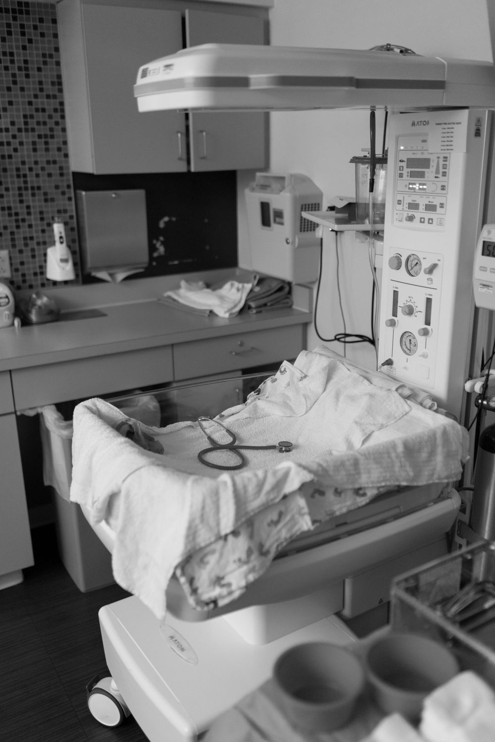 Medical equipment and hospital bed setup in a clinical room with monitors and white linens.