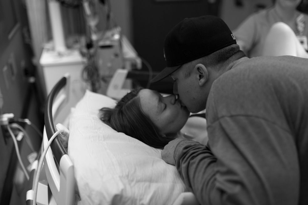 Black and white photograph showing tender moment during medical care in hospital setting.