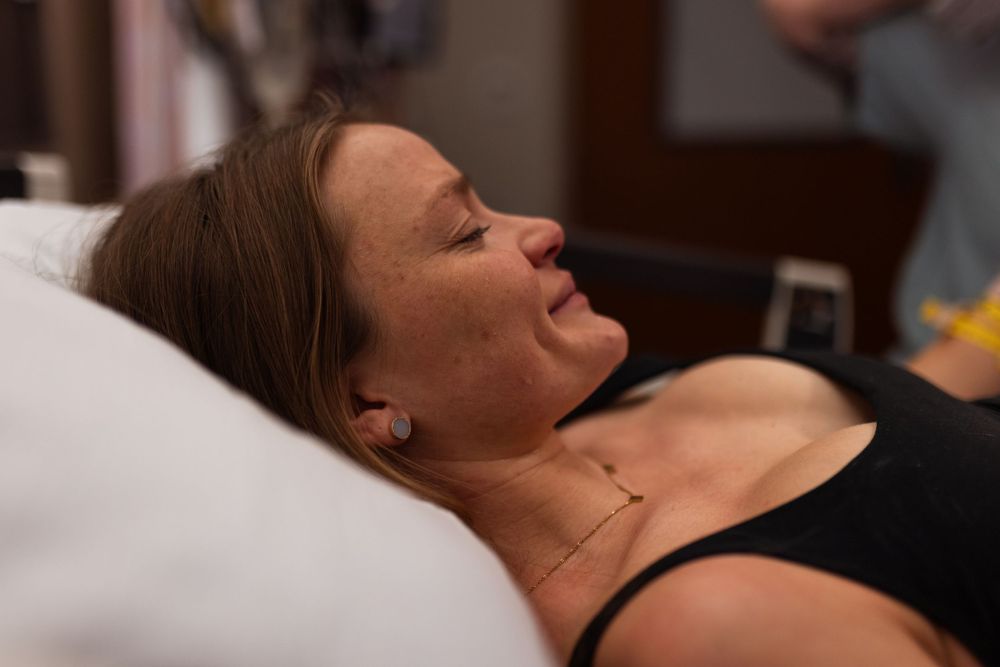 A patient rests with closed eyes in a hospital bed during labor.