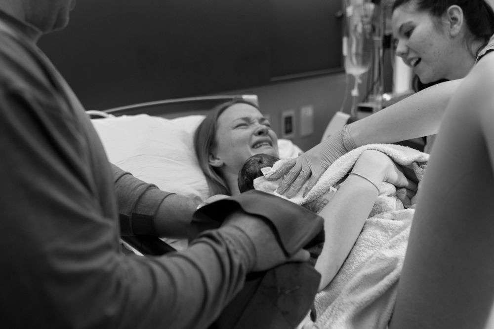 Healthcare providers assist patient during medical procedure in black and white image.
