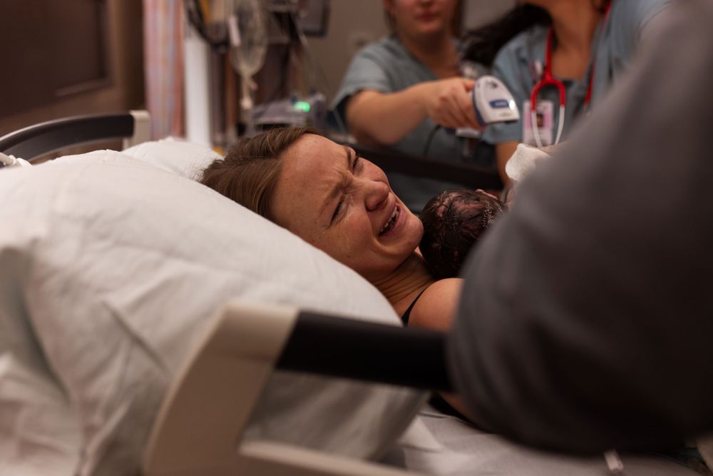 A woman in labor experiencing contractions on a hospital bed during childbirth.
