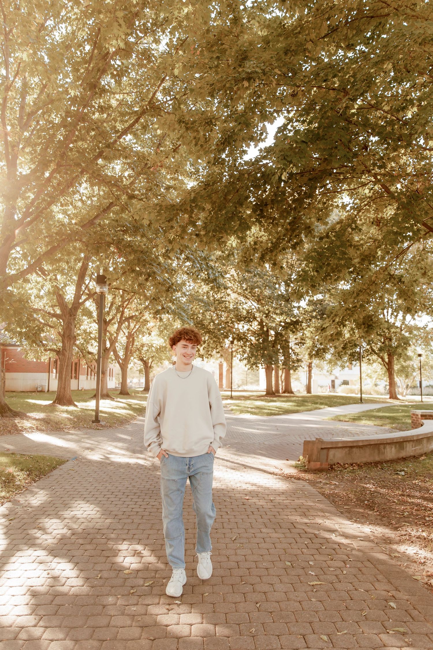 Person standing on brick pathway under golden sunlit trees in an autumn park setting with warm vintage tones.