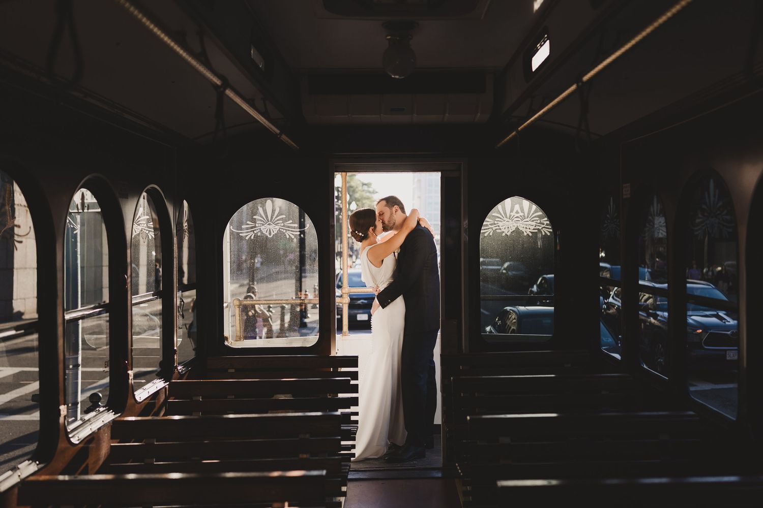 Bride and groom share a romantic kiss inside a vintage trolley car on their wedding day.
