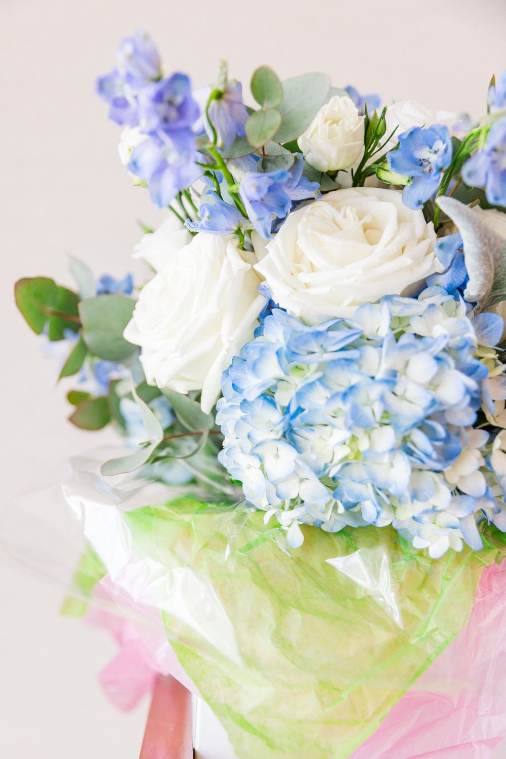 Elegant wedding bouquet featuring white roses, blue hydrangeas, and eucalyptus leaves.