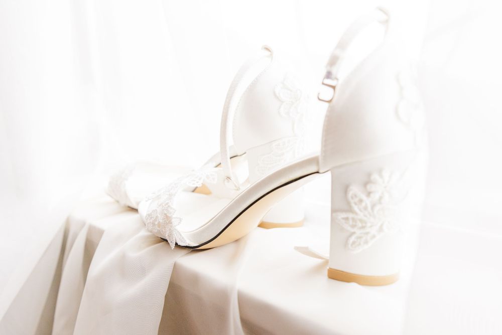 White bridal shoes with elegant bow details sit against a soft white background.