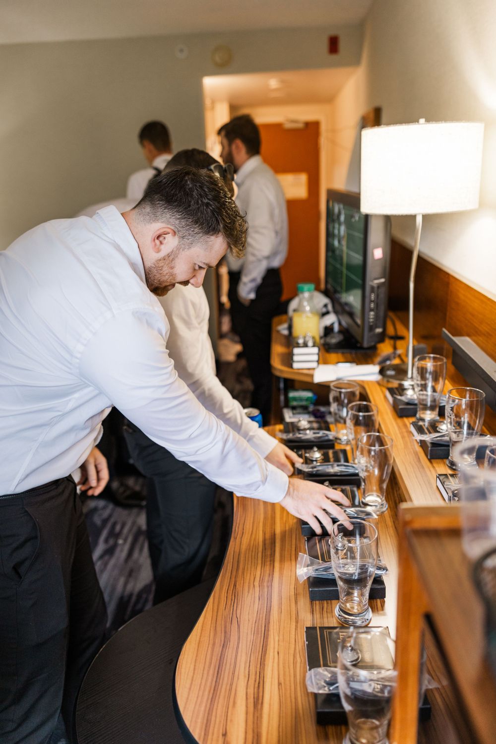 Person setting up drinks and glasses on wooden counter.