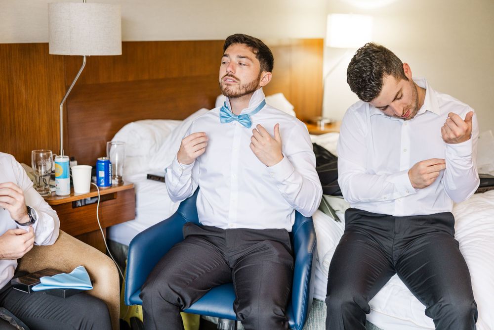 Group preparing formal attire in hotel room setting.