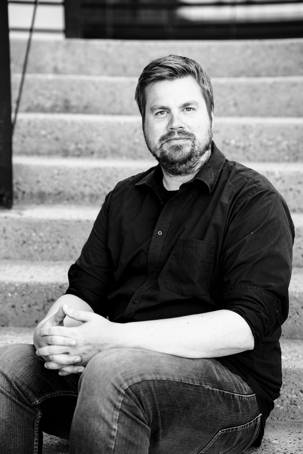Black and white portrait series showing a person in dark clothing sitting on concrete steps from different angles.