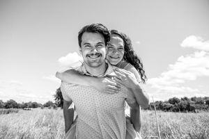 A joyful couple embraces in a sunny meadow on a bright summer day, captured in black and white.